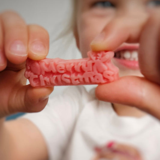 Child holding a red playdough Christmas message close to the camera