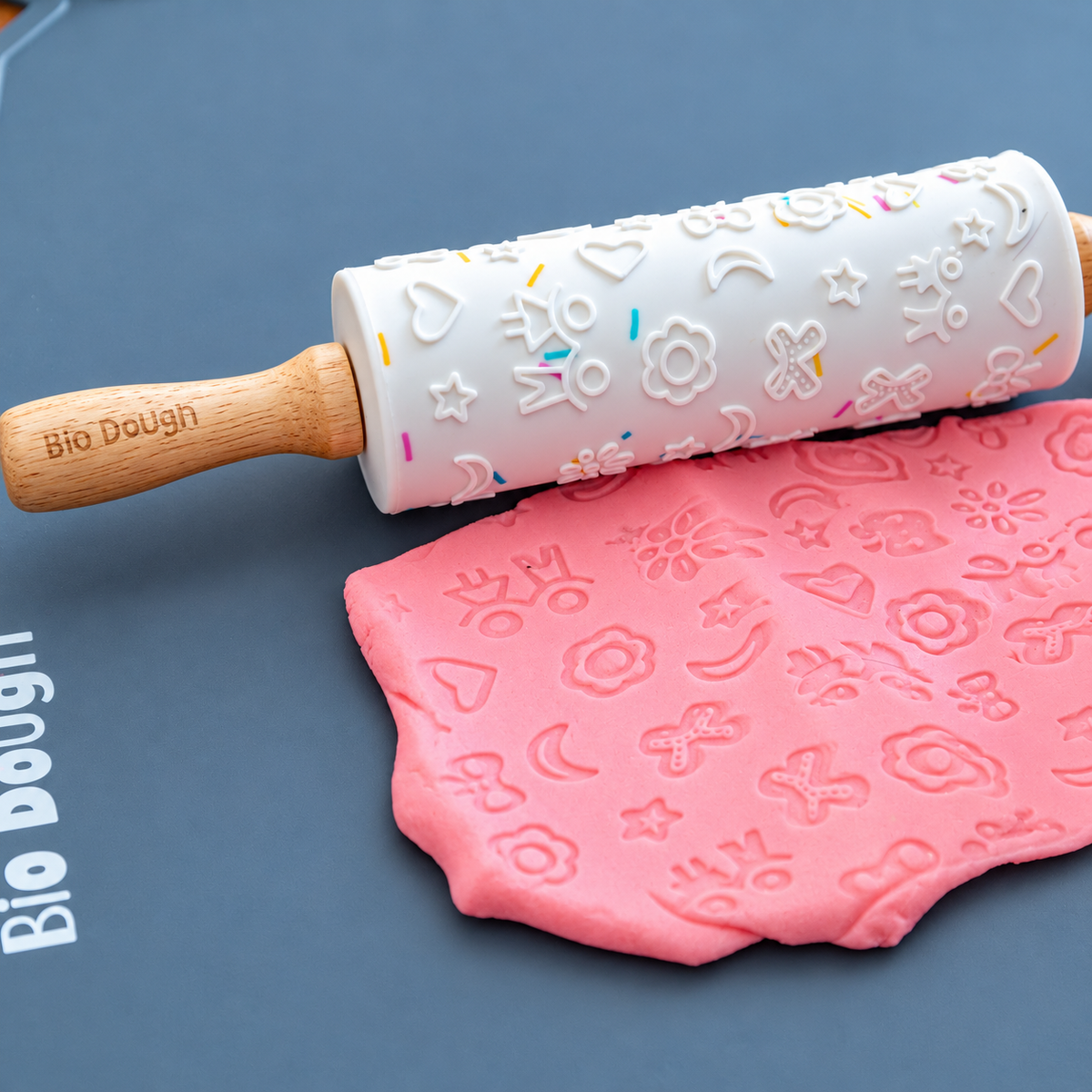 Bio DoUgh embossed silicone rolling pin beside pink patterned playdough