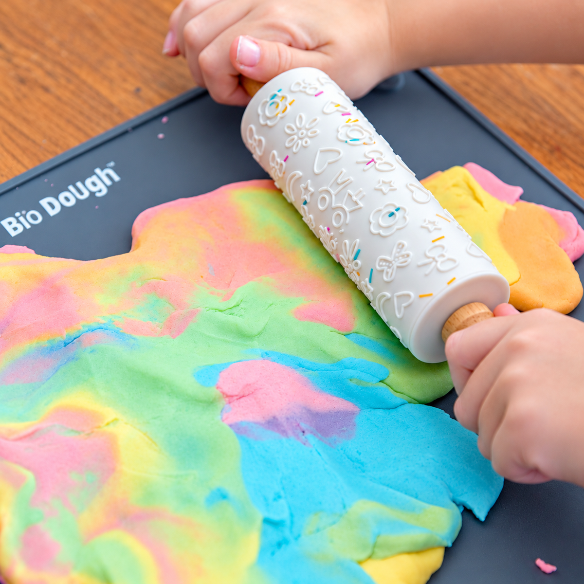 Child using Bio DoUgh embossed rolling pin with colourful rainbow playdough