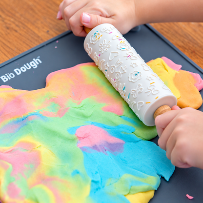Child using Bio DoUgh embossed rolling pin with colourful rainbow playdough