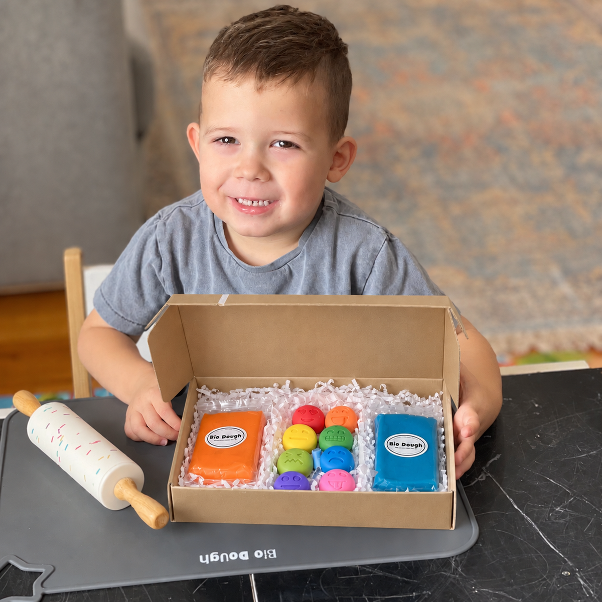 Child holding a Bio DoUgh Emotion Emoji figurine and playdough gift set
